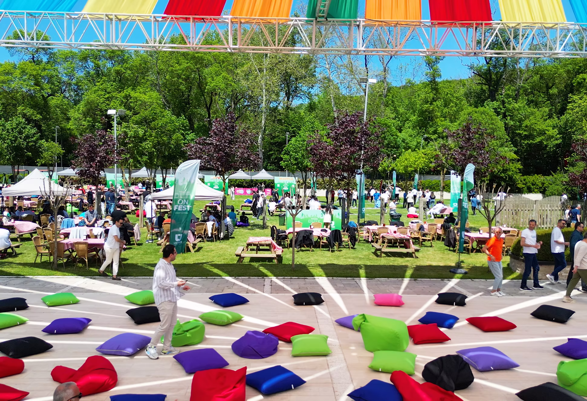 Event Garden’da renkli minderler ve ağaçlar arasında etkinlik alanı